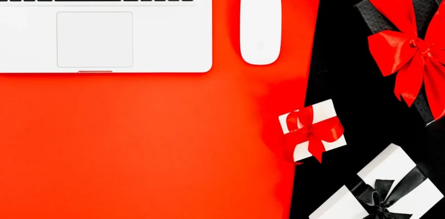Laptop mouse on red and black background with gift boxes representing eCommerce